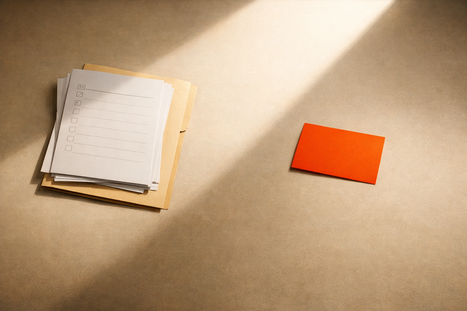 A warm-lit workspace table viewed from above. On the table: a carefully arranged set of blank review rubrics, a single orange-gold card standing out among whites and off-whites, and a threshold of light crossing the surface. There are no visible people, devices, or text—just evidence of process, selection, and focused judgement. The scene is minimal, with generous negative space and editorial focus on the artifacts and light, using the Roast & Rise orange and warm neutrals palette. No words, labels, numbers, or logos.